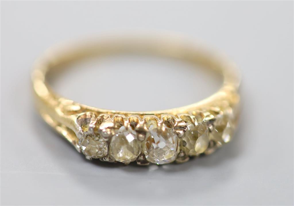 An early 20th century yellow metal and graduated five stone diamond set ring, size O, gross 2.6 grams.